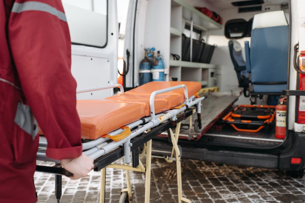 A paramedic loads a stretcher into an ambulance, showcasing emergency medical services in action.